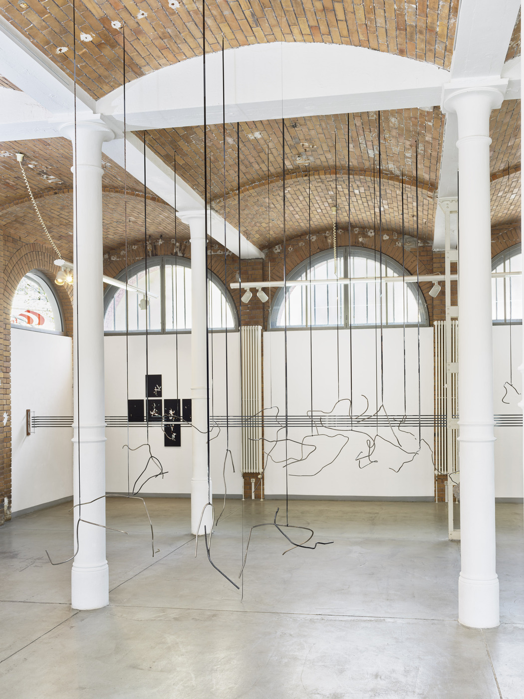 Suspended wire installation by Vanessa Enríquez inside industrial gallery architecture.