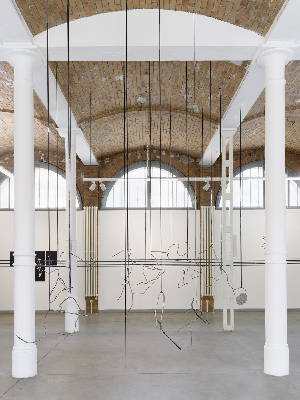 Front view of suspended wire installation by Vanessa Enríquez in industrial exhibition space.
