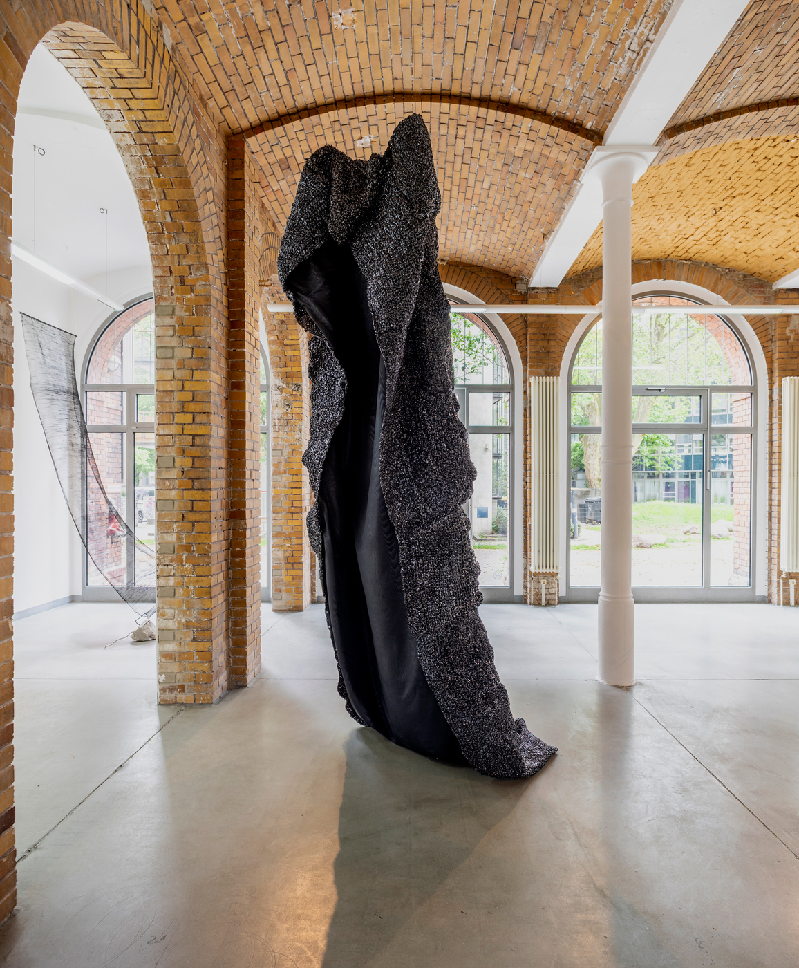 Large black sculptural textile installation inside gallery space by Vanessa Enriquez