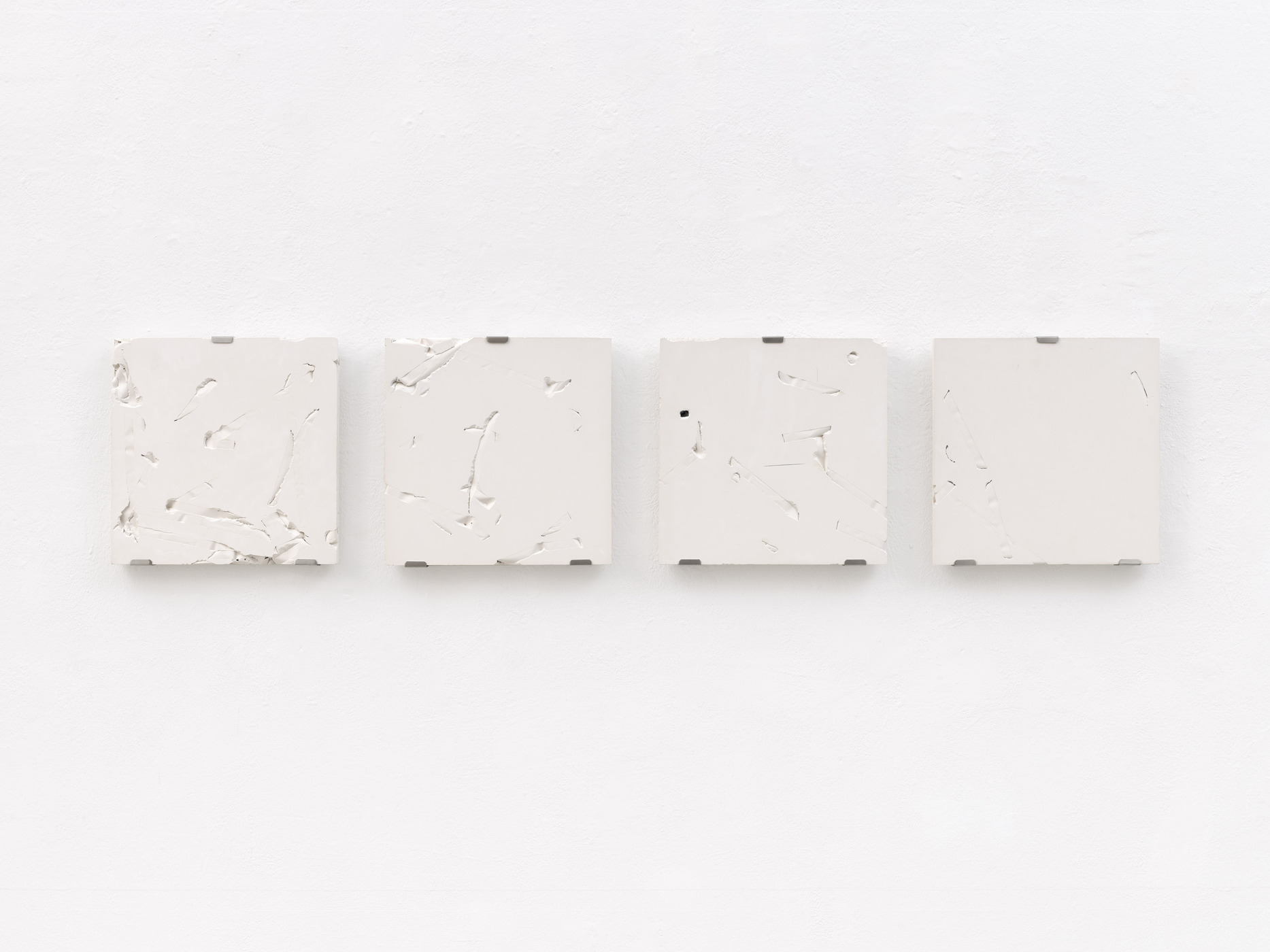 Minimal white relief sculpture series by Vanessa Enríquez mounted on gallery wall.